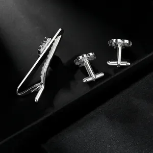 Detailed close-up of clover tie clip and cufflinks set with matte and polished finish