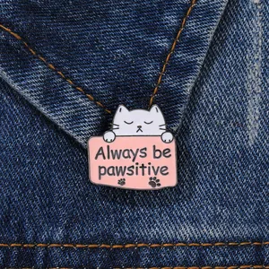 Detailopname van Always be pawsitive emaille speld op donkere denim stof