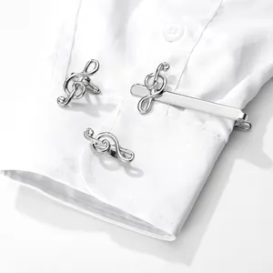 Detail view of silver treble clef cufflinks and tie clip set on a white dress shirt cuff