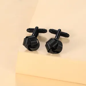 Macro view of black braided knot cufflinks with metallic T-bar on minimalist pedestal