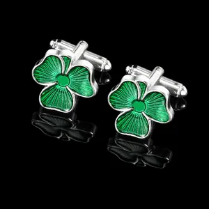 Silver cufflinks with green shamrock enamel design and rotating bar on black background