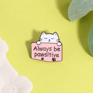 Detail van de schattige kattenemaille pin met Always be pawsitive tekst op roze bordje