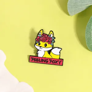 Dettaglio della spilla a volpe in smalto giallo con corona di rose e testo Feeling Foxy