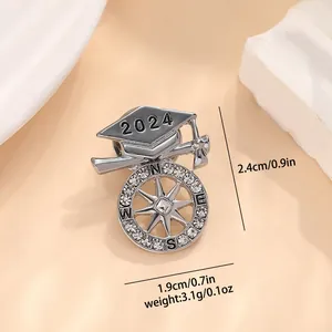 Macro view of 2024 graduation cap brooch with compass charm and crystal details
