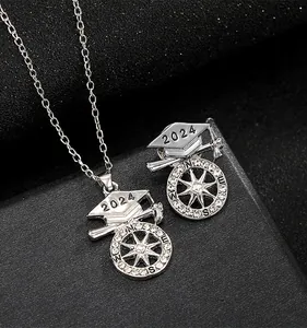 Detailed macro view of silver 2024 graduation jewelry set with compass and cap charms