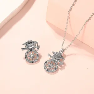 Detailed view of 2024 graduation jewelry set with doctoral cap and compass pendants