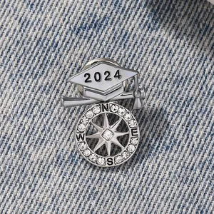 Close-up of 2024 graduation cap brooch with silver compass and sparkling rhinestones