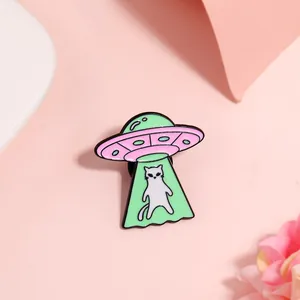 Cute UFO cat enamel pin in mint green and pink colors on a soft pastel background