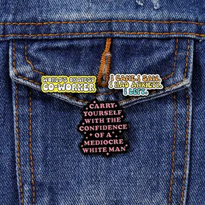 Three creative enamel pins with witty text pinned on a blue denim jacket pocket