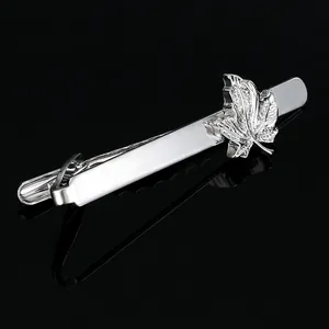 Detailed view of silver maple leaf tie clip on reflective black surface with clear veins