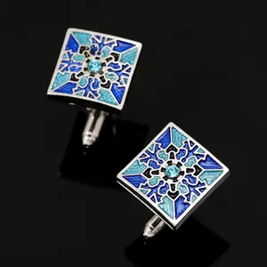 Detail of square silver cufflinks with blue geometric enamel patterns and small crystals