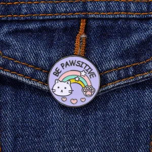 Detail der Be Pawsitive Emaille-Anstecknadel mit Regenbogen-Katze auf Jeansjacke