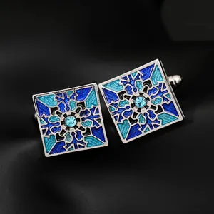 Close-up of square cufflinks with blue enamel patterns and center crystals on black background