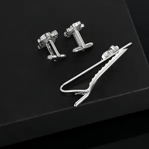 Polished silver leaf cufflinks and tie clip set displayed on a matte black background