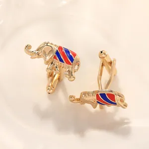 Detailed macro view of golden elephant cufflinks with colorful enamel stripes on light surface