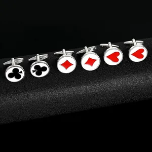 Macro shot of poker themed cufflinks with club diamond and heart patterns on black surface