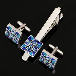 Detailed macro view of silver tie clip and cufflinks with blue enamel floral pattern