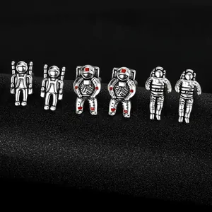 Macro shot of silver astronaut cufflinks with red and black enamel details on dark stand