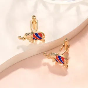 Detail of elephant cufflinks with red and blue enamel in gold finish on a display stand