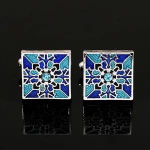 Square silver cufflinks with blue geometric enamel and crystal, mirrored on black background