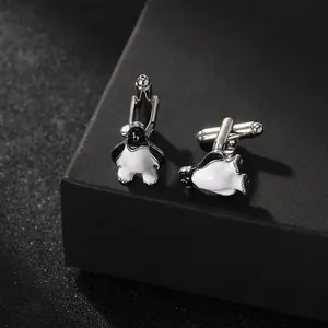 Detailed close-up of penguin cufflinks in black and white enamel on a dark jewelry box