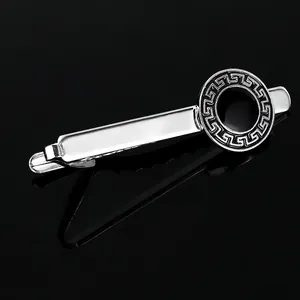 Detail of silver tie clip with black Greek key pattern on a mirror black background