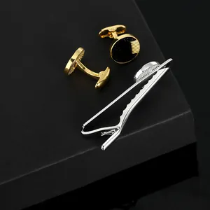 Detailed view of gold round cufflinks and silver tie clip set in a black gift box