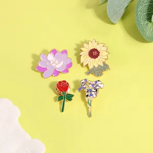 Ensemble de quatre broches en émail floral avec tournesol, rose, lotus et iris sur fond jaune