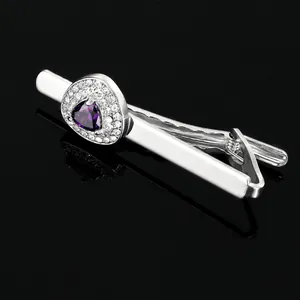 Macro shot of silver tie clip with purple triangular crystal and small white diamonds