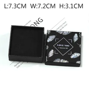 Vue détaillée d'une boîte cadeau noire avec plume argentée et dimensions 7,3x7,2x3,1cm