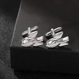 Macro shot of silver rocket-shaped shirt cufflinks on a black premium gift box edge
