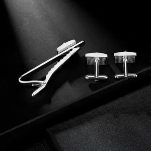 Macro view of silver tie clip and cufflinks set with square texture and polished finish