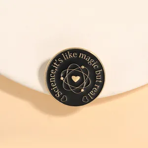 Macro view of a black enamel science pin with gold atomic orbits and heart symbol