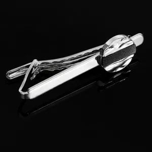 Polished silver tie clip with a black matte round inlay on a sleek dark background