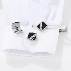 Gros plan des boutons de manchette et pince à cravate sur une manche de chemise blanche