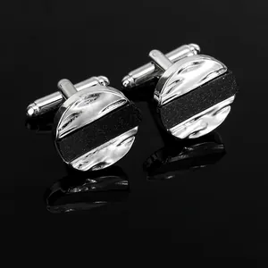 Macro detail of silver round cufflinks with wave pattern and black glitter inlay