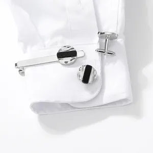 Silver and black round cufflinks with matching tie clip set on white French shirt cuff