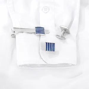 Dettaglio di gemelli d'argento e fermacravatta con smalto blu a righe su camicia bianca