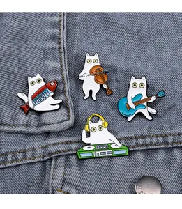 Details von vier weißen Katzen-Emaille-Pins mit Musikinstrumenten auf einer Jeansjacke