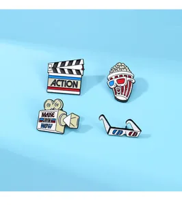 Detailed close-up of cinema-themed enamel pins featuring popcorn and movie camera