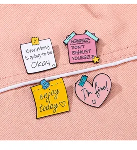 Vue détaillée de quatre pins émaillés colorés avec phrases motivantes sur tissu