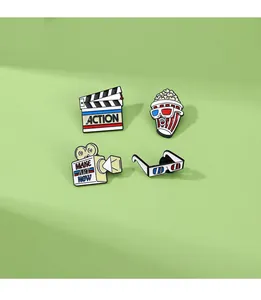 Macro shot of 4-piece cinema enamel pin set including popcorn and film camera