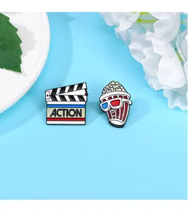 Detailed set of movie themed enamel pins featuring a film clapperboard and 3D popcorn bucket