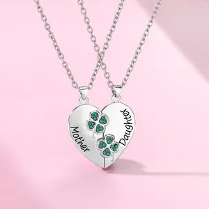 Detail of interlocking heart necklaces with green clover and Mother Daughter engraving