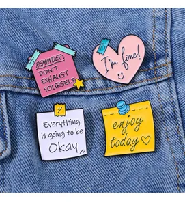 Détail de quatre épinglettes en émail avec citations sur tissu en denim bleu