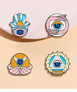 Close-up of four enamel pins with Evil Eye, Hamsa Hand, and mystical eye symbols