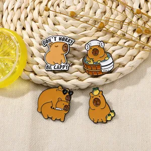 Cute capybara enamel pin set with orange and flower accents on a woven texture background