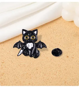 Detail of black cat enamel pin with bat wings and a small dagger on a warm background