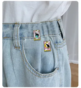 Cat tarot enamel pins with The Moon and The World designs pinned on denim jeans