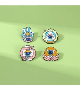 Close-up of four enamel eye pins featuring Hamsa hand and mystic sun symbols